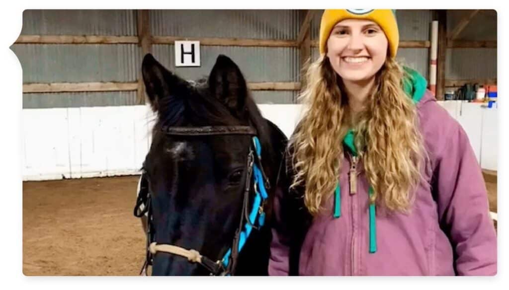 young female next to black horse