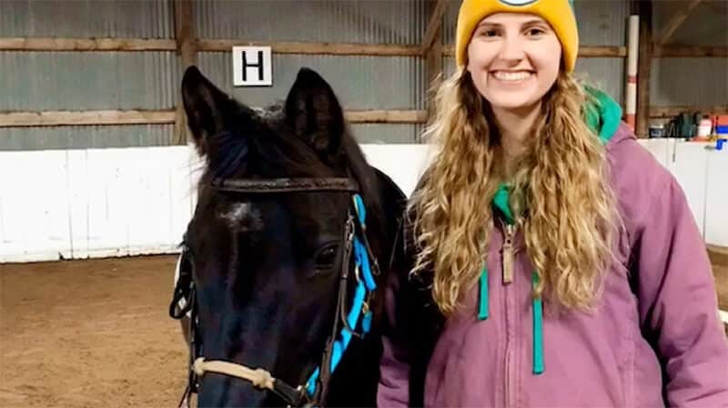 young female next to black horse